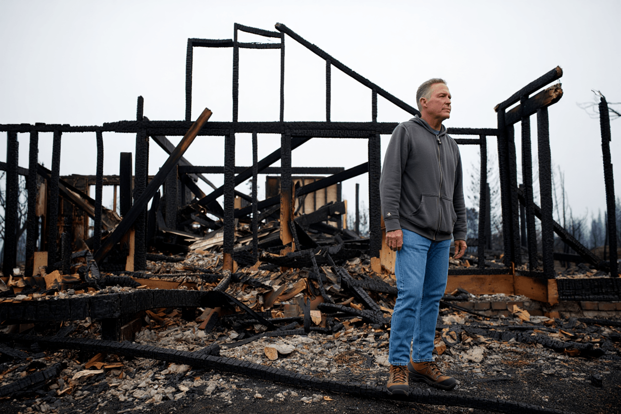 A California homeowner standing in front of a fire-damaged house